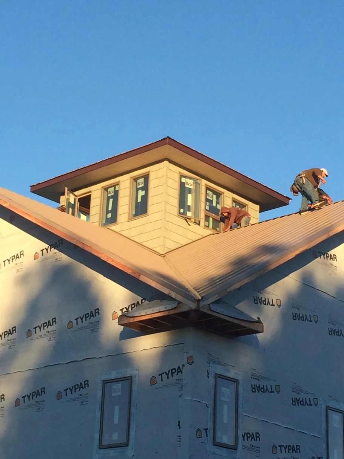 Roofers working around a rooftop cupola on a new metal roof at sunset — Roof Waterproofing in Williamsburg by Roofing Brothers